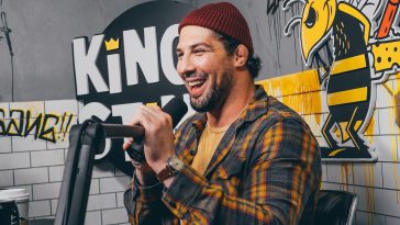 man in red knit cap and yellow and black plaid dress shirt holding microphone