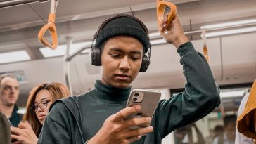 man in train holding smartphone