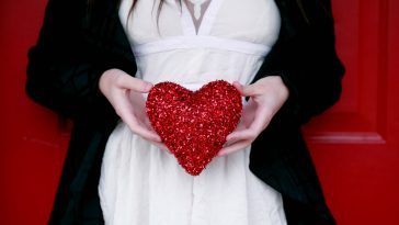 women holding red heart pillow