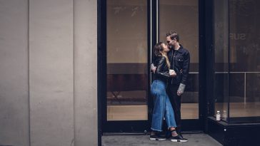 photo of man and woman kissing beside glass doors