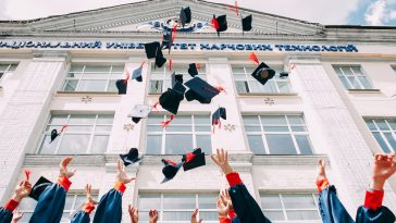 group of fresh graduates students throwing their academic hat in the air