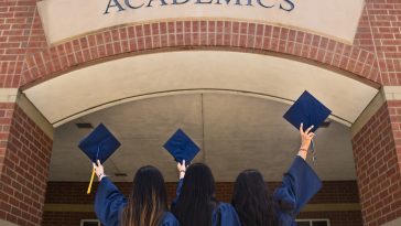 three girls in graduation gowns hold their caps in the air