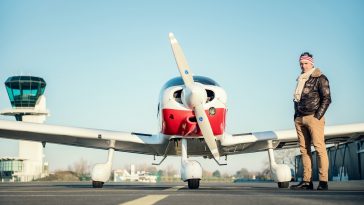 man standing near red biplane