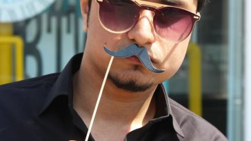 man holding black mustache party props